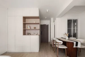 Bright, contemporary home entrance featuring clean white walls, custom open shelving, and a sleek dining table setup.